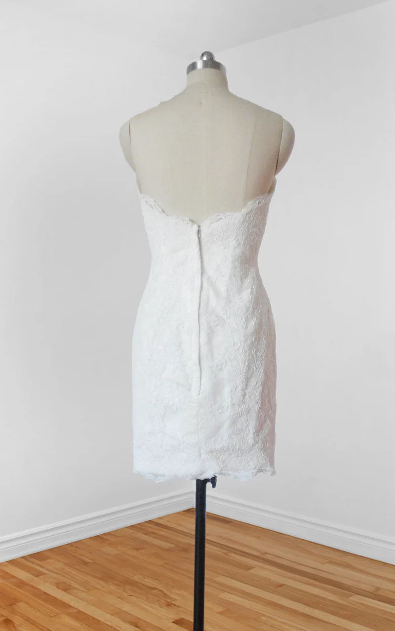 Model wearing an elegant short white lace wedding dress with spaghetti straps, side view.