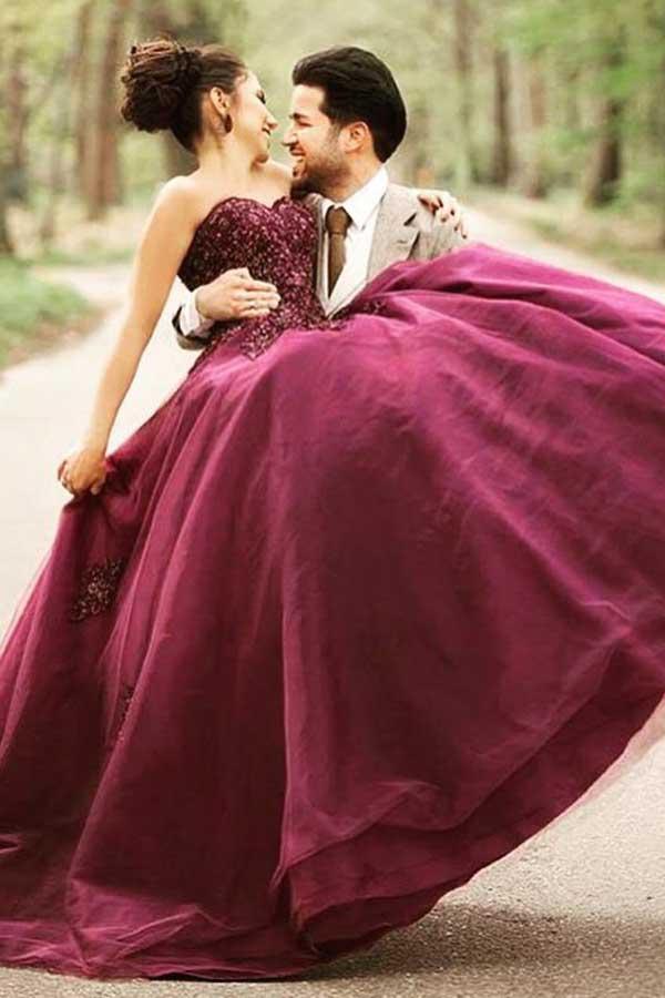 Side view of the burgundy A-line wedding dress, showcasing the flowing tulle skirt and floral embellishments.