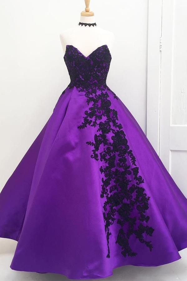 Full length view of a purple ball gown prom dress with black appliques.