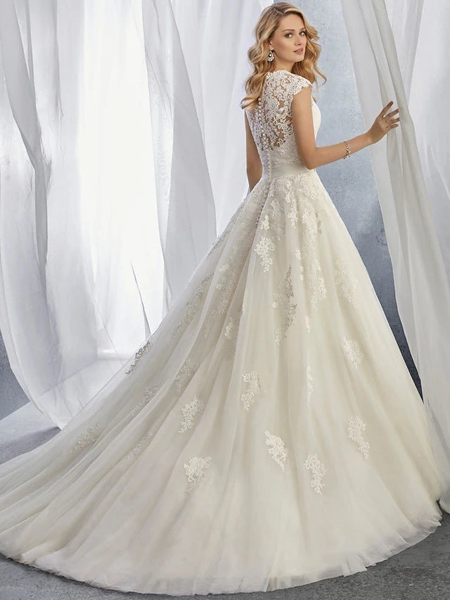 Bride posing in a cap sleeve sweetheart lace wedding dress.