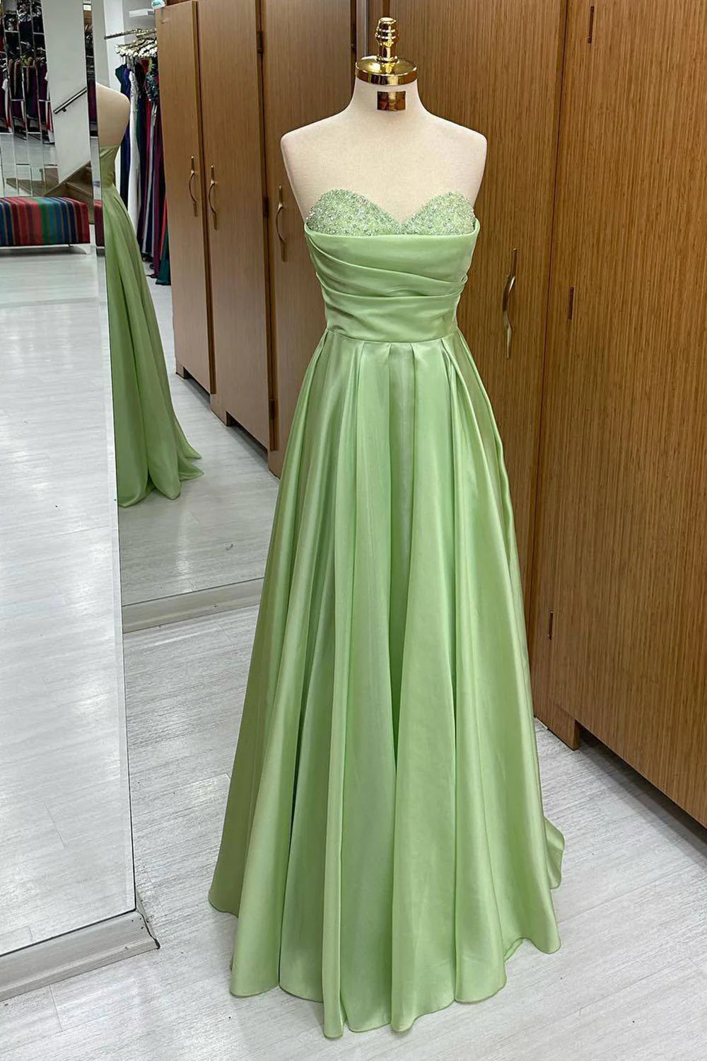 Model wearing an elegant green sweetheart long sequined prom dress.