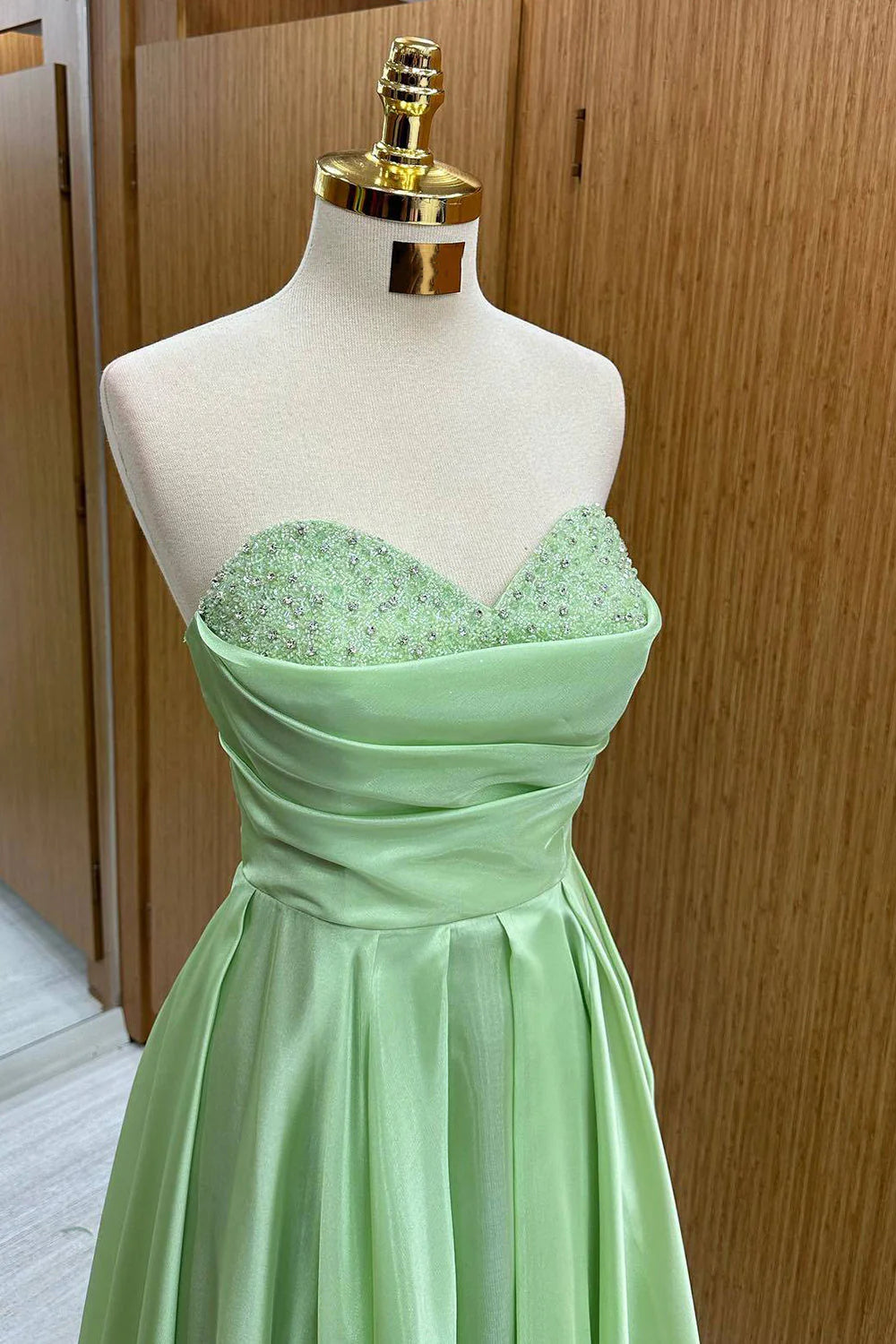 Full view of a green sweetheart long sequined prom dress.