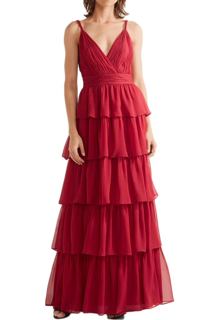 Woman wearing a long V-neck tiered chiffon prom dress with spaghetti straps.