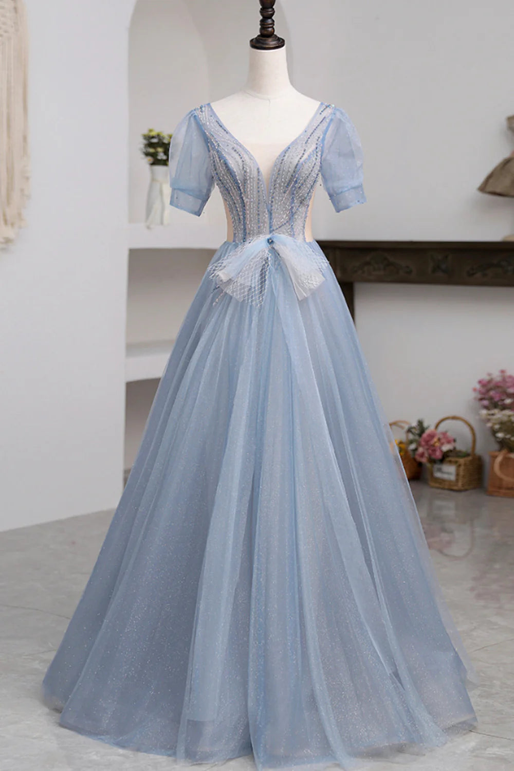 Model wearing an elegant light-colored tulle short sleeve floor length prom dress.