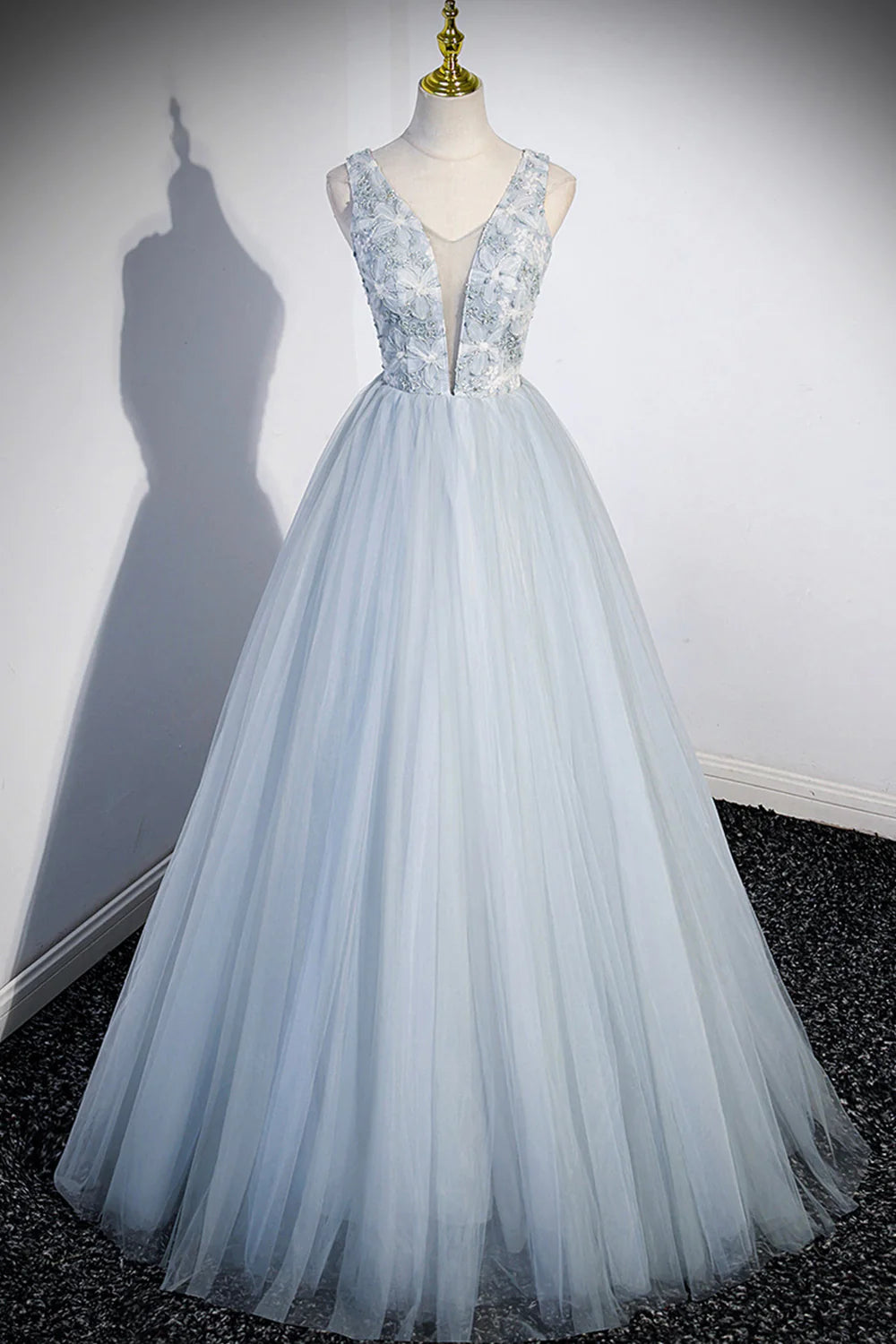 Model wearing an elegant long tulle V-neck prom dress, posing gracefully.
