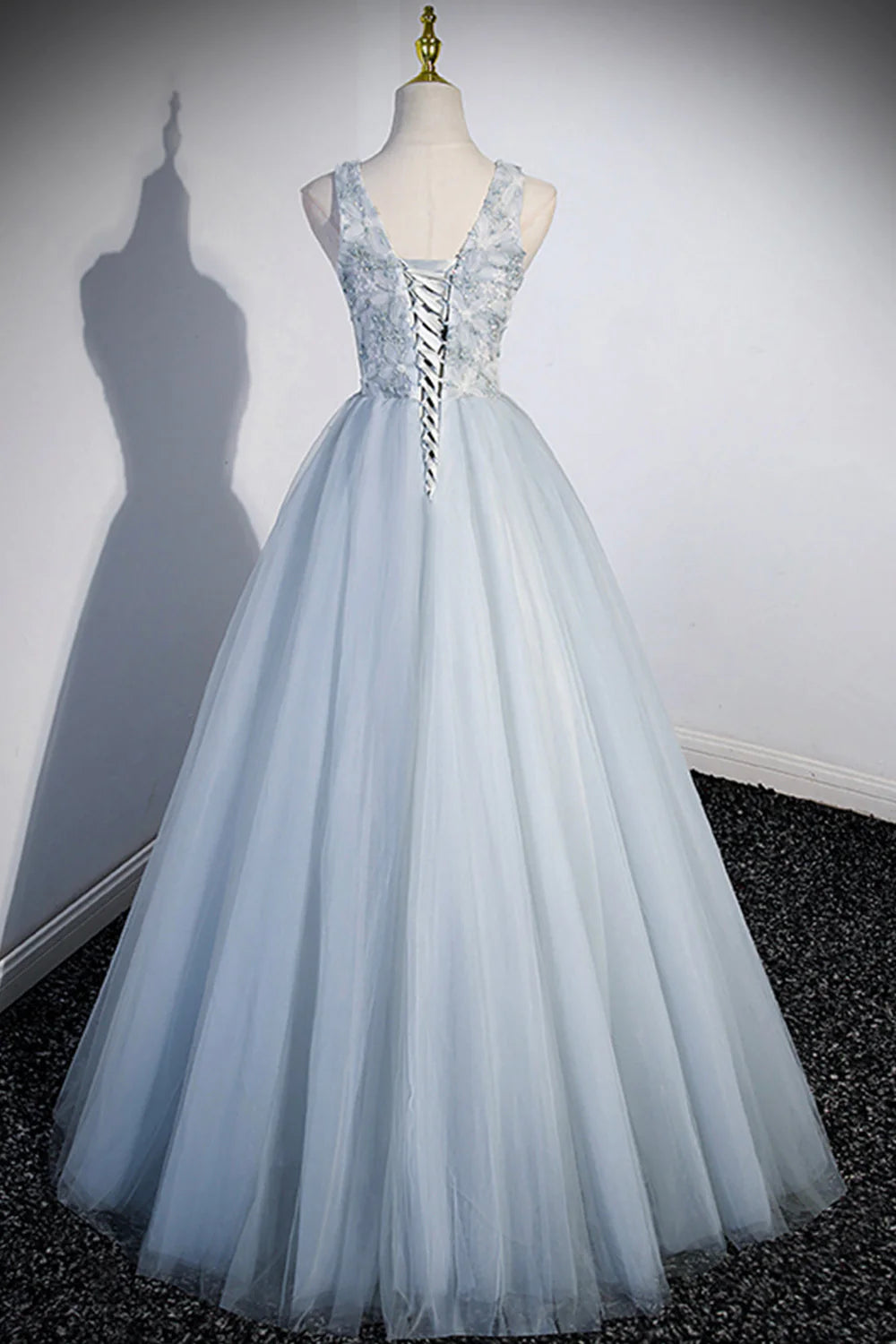 Back view of a model in a long tulle V-neck prom dress, showcasing the flowing skirt.