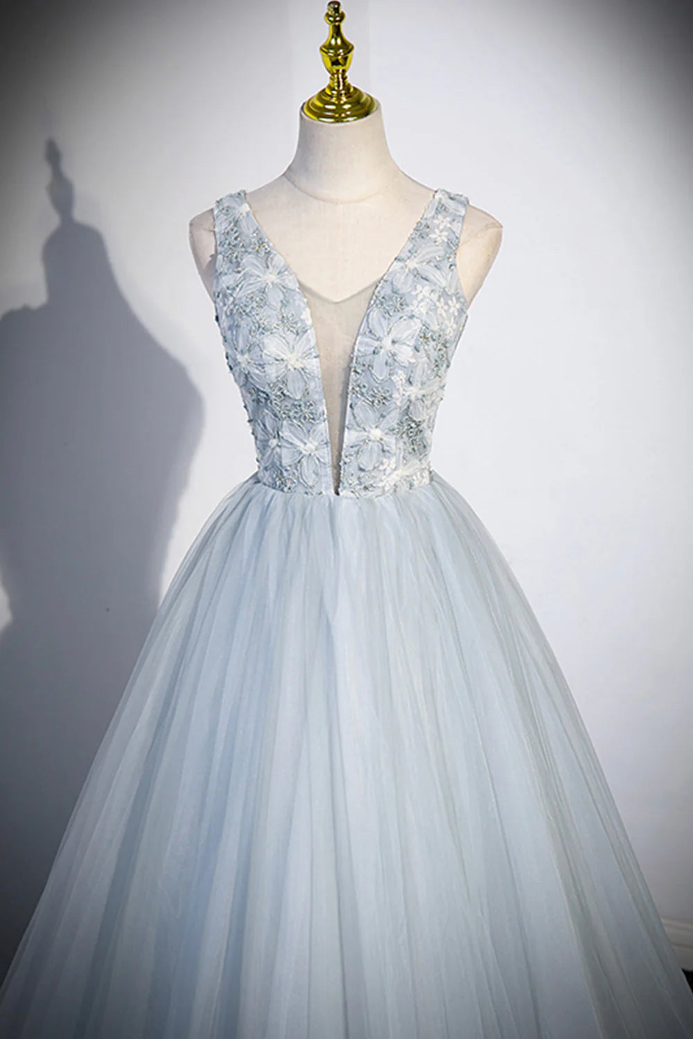 Model gracefully walking in a long tulle V-neck prom dress, showing movement of the skirt.
