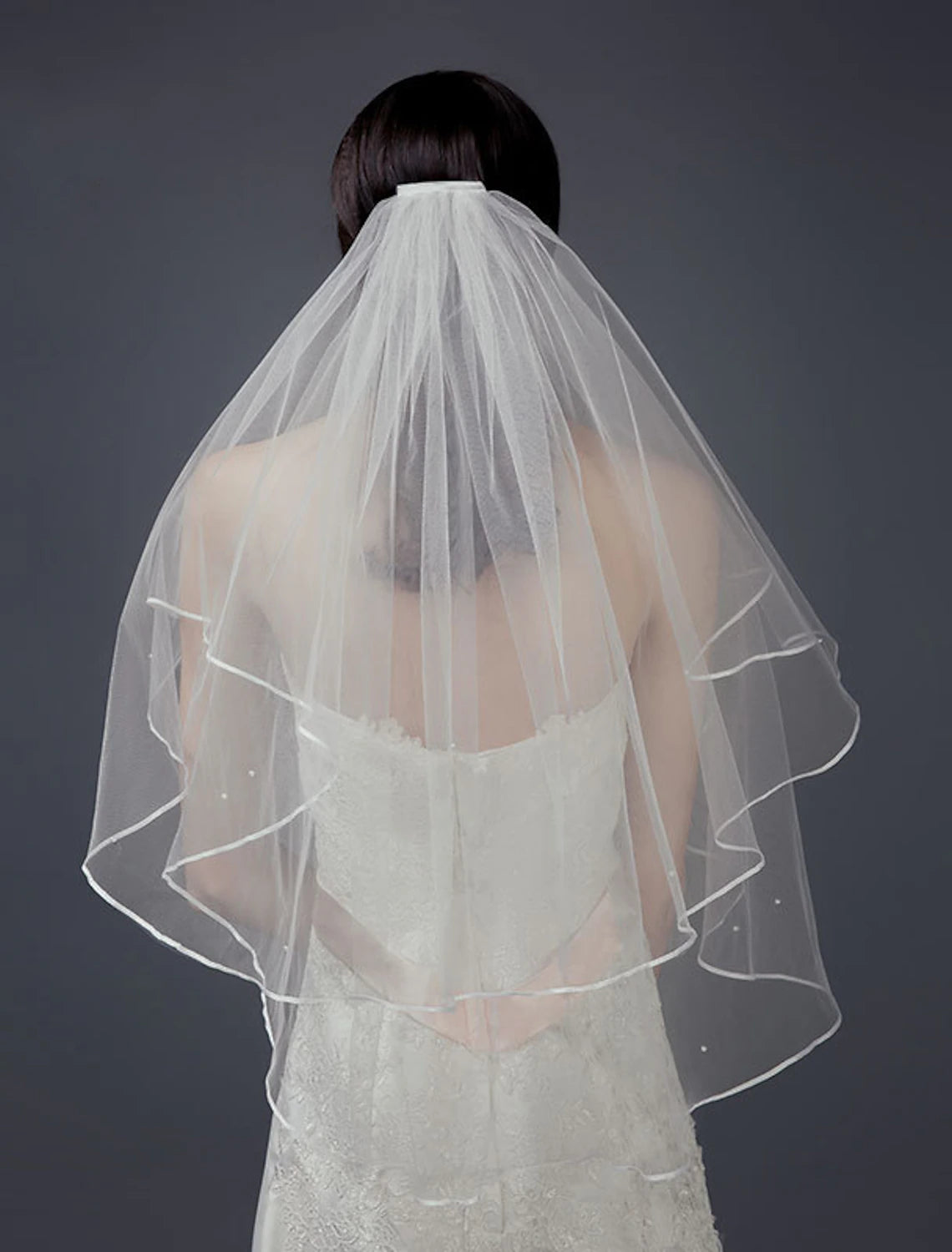Close-up of a two-layer short ivory bridal veil with a delicate comb edge.