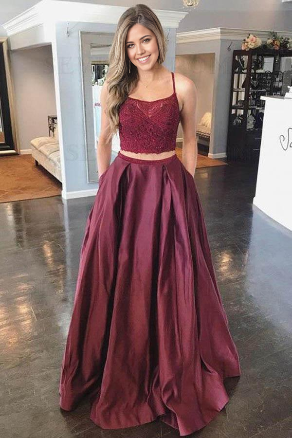Model wearing a two-piece A-line burgundy prom dress with a lace top and spaghetti straps.