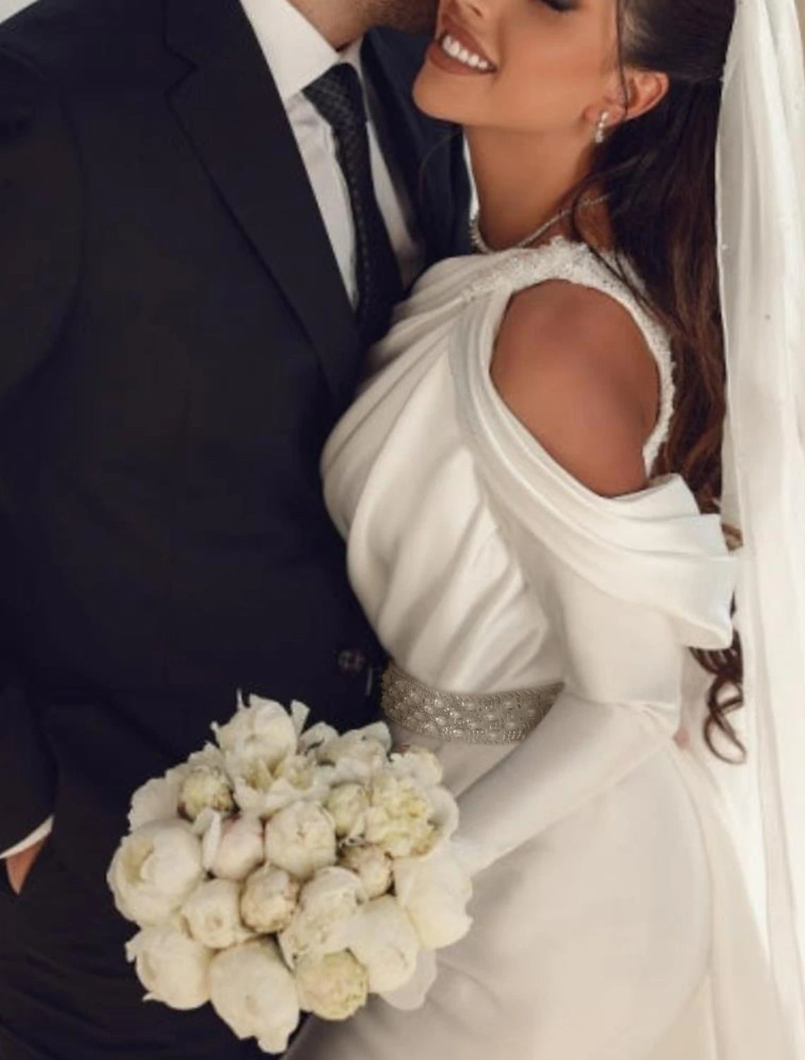 Close-up of the one-shoulder detail and long sleeve of the satin wedding dress.