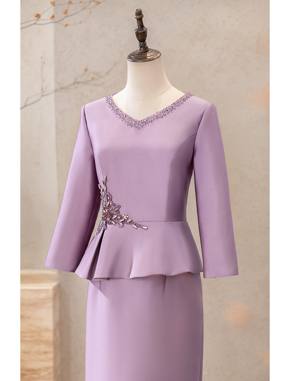 Close-up of the appliques on the long sleeve satin cocktail dress.