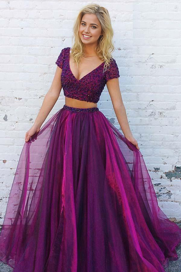 Model wearing a two-piece purple tulle prom dress with V-neck, short sleeves, and beading.