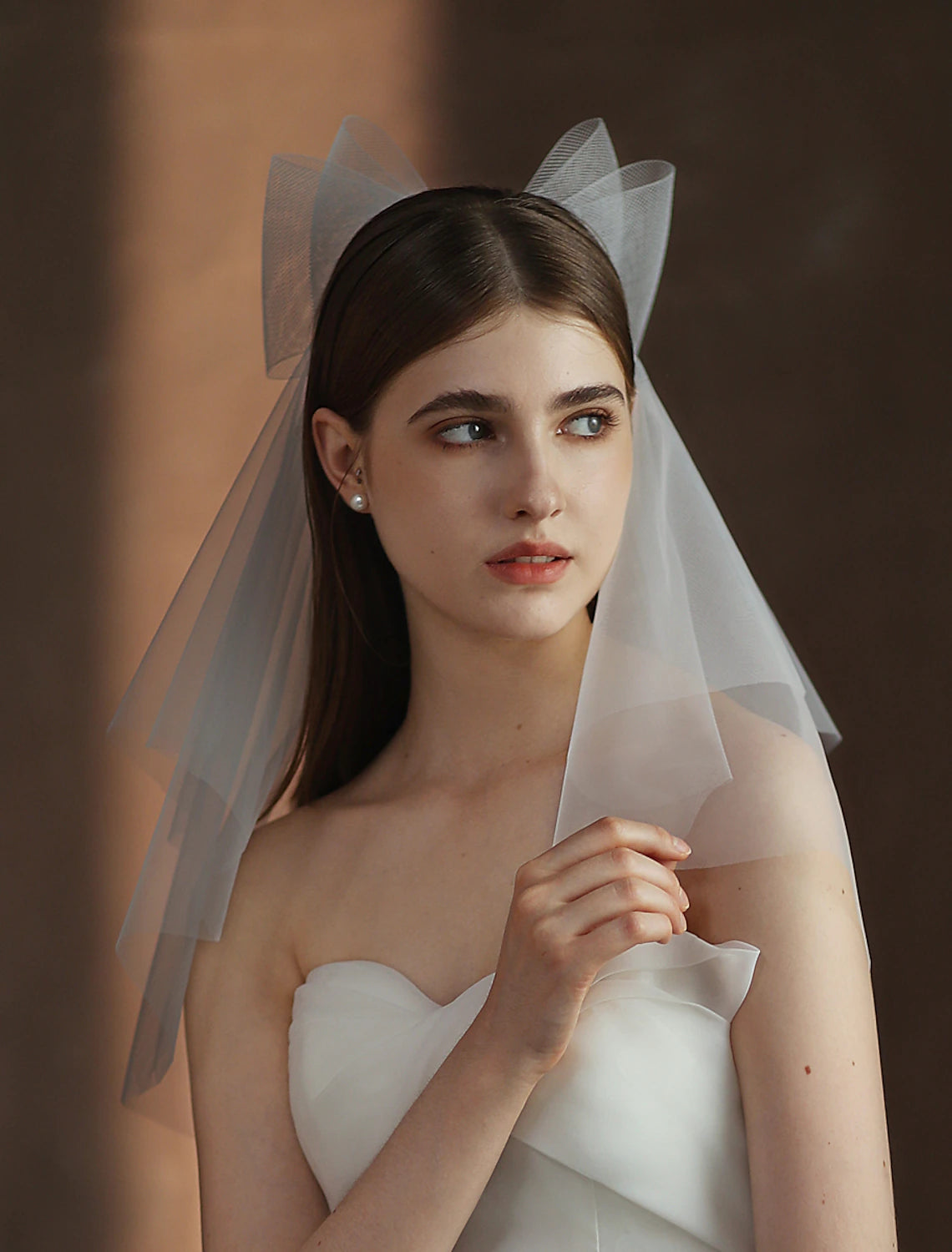 Back view of a bride with a flowing two-tier elbow wedding veil.