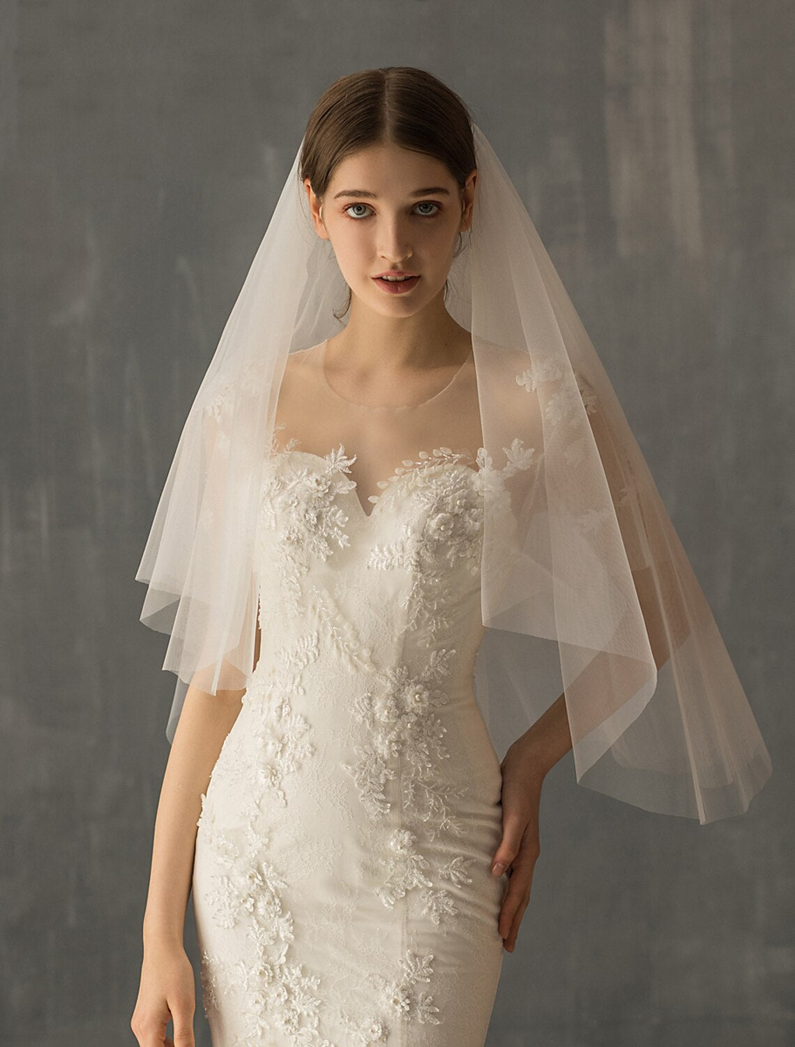 Bride from the side, showcasing the delicate layers of an elbow wedding veil.