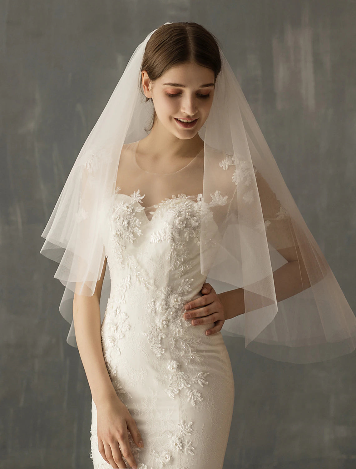Bride posing with a flowing two-tier elbow wedding veil.