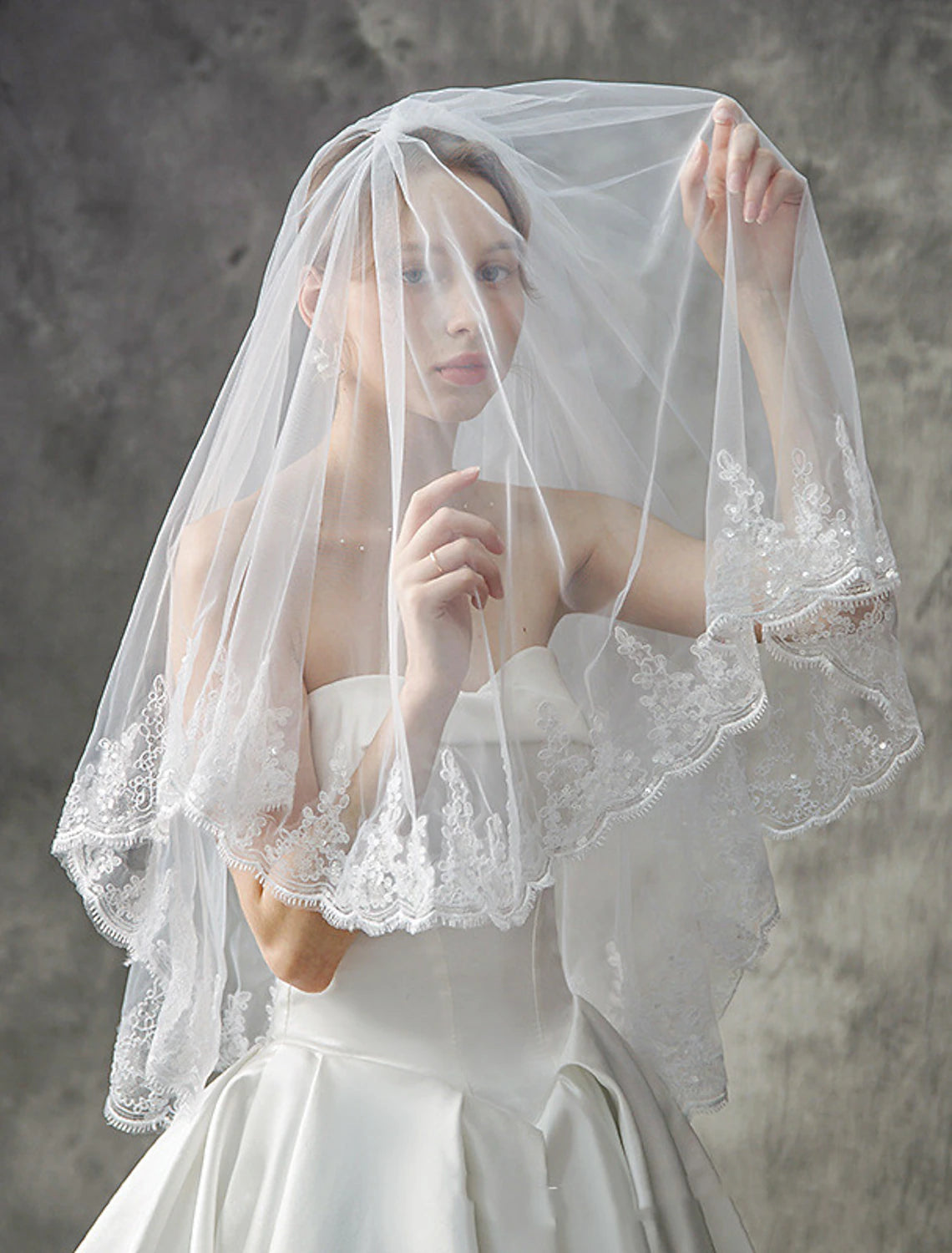 Bridal model wearing a two-tier elbow-length wedding veil.