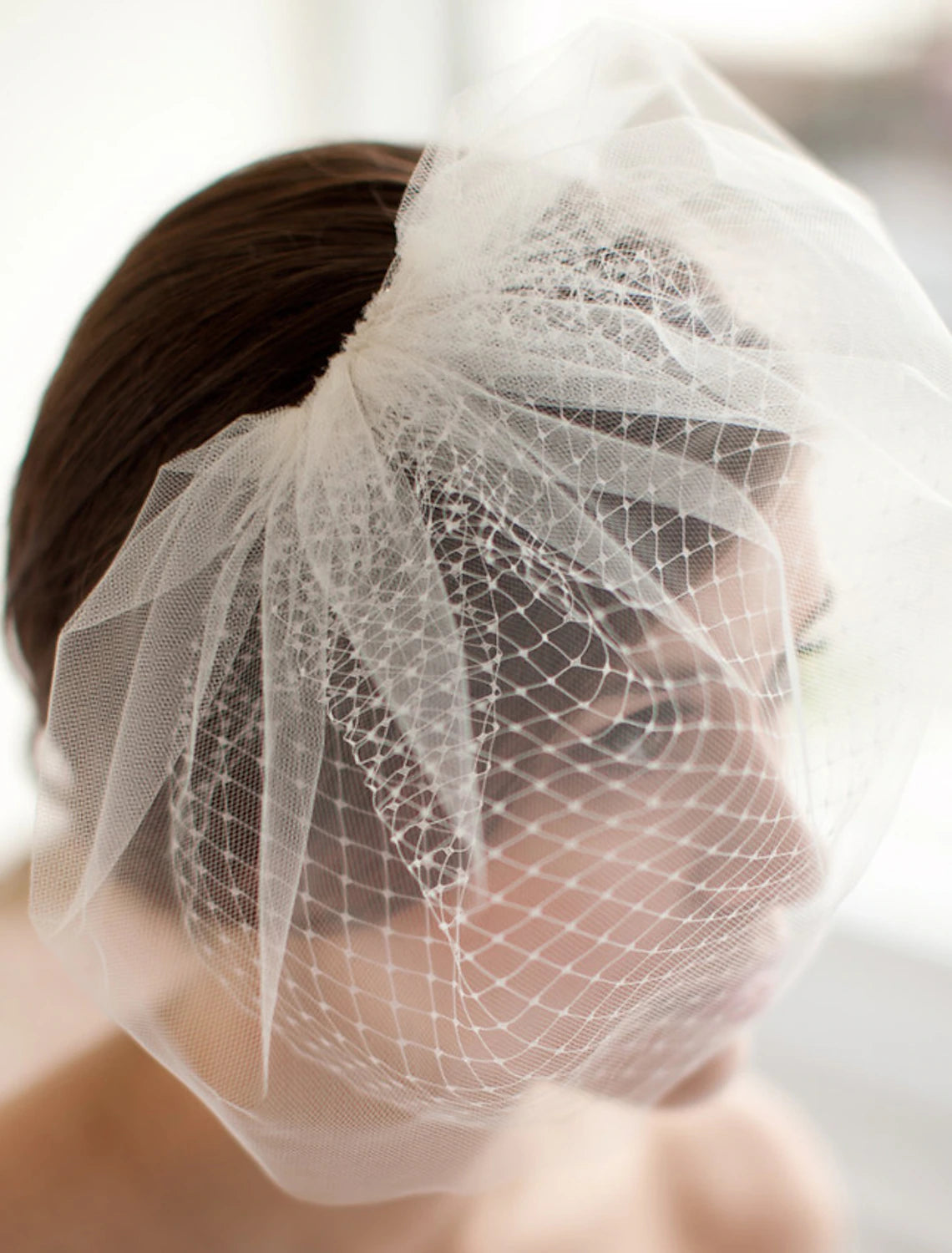 Model wearing an elegant two-tier white tulle wedding veil.