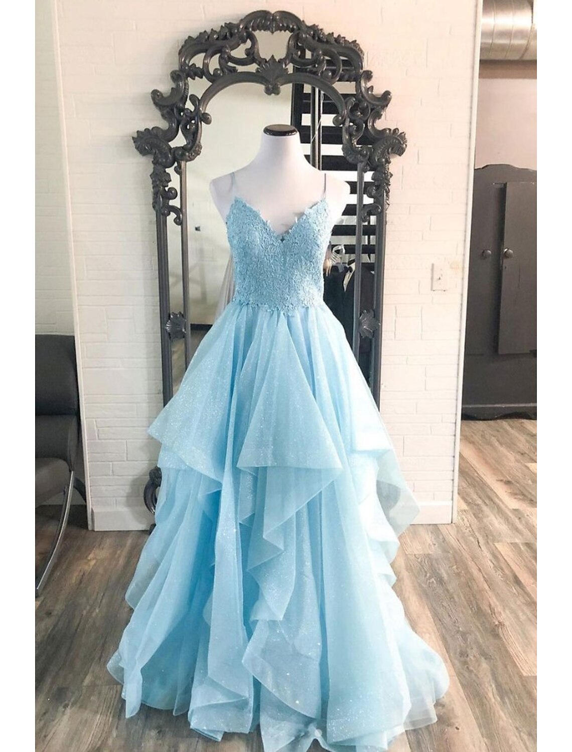 Back view of a sleeveless V-neck ball gown, showing the backless design and pleats.