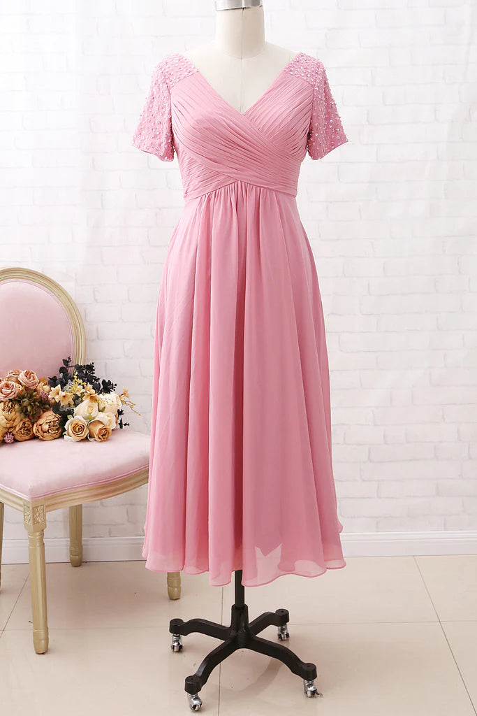 Model wearing an elegant V-neck chiffon A-line tea length mother of the bride dress with short sleeves.