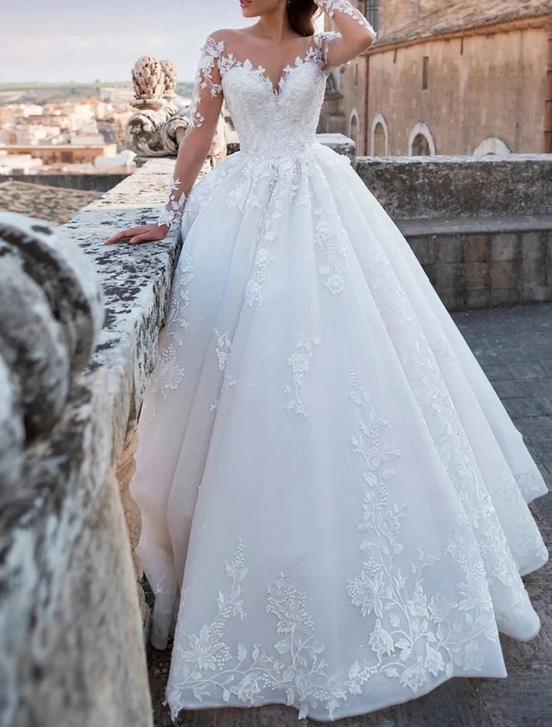 Side profile of the ball gown wedding dress, showcasing the long sleeves and flowing chapel train.