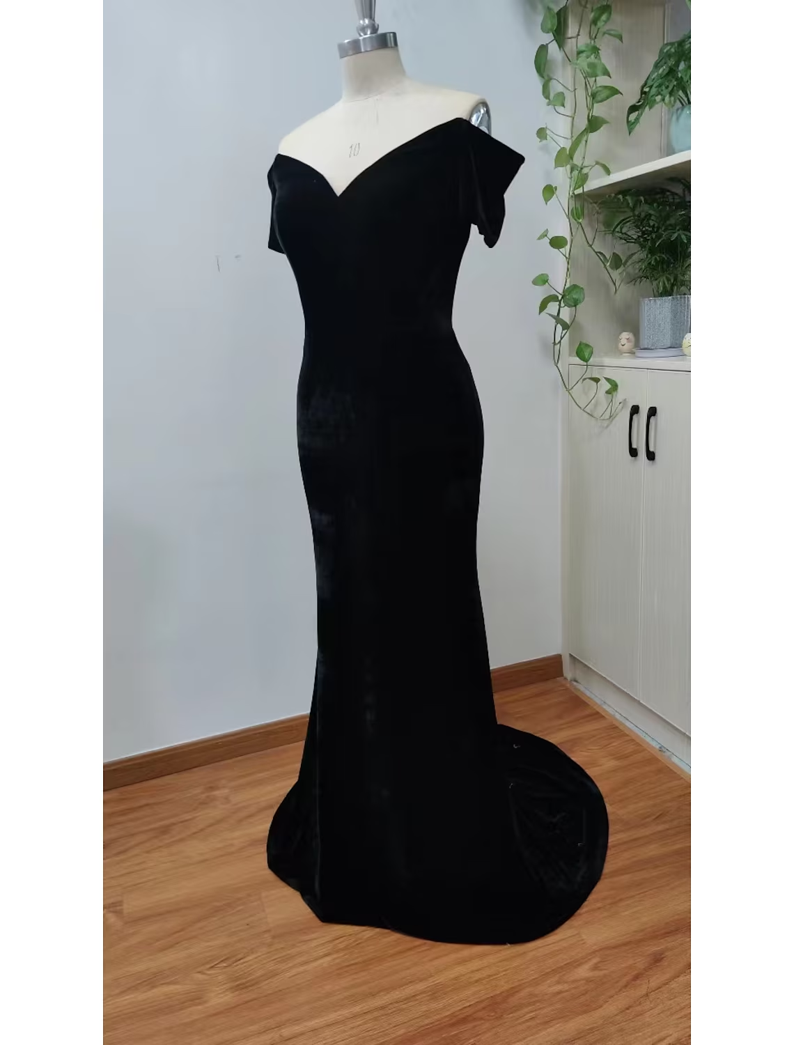 Woman wearing an elegant black velvet mermaid evening gown with a V-neck and short sleeves.