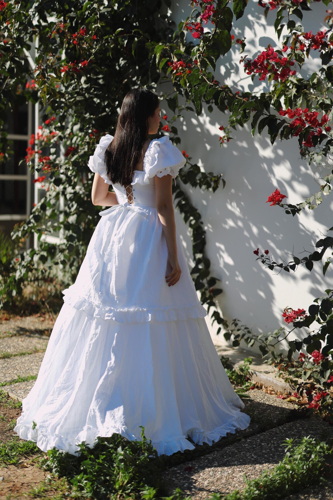Full length view of a white A-line corset dress with a V-neck and elegant cape.
