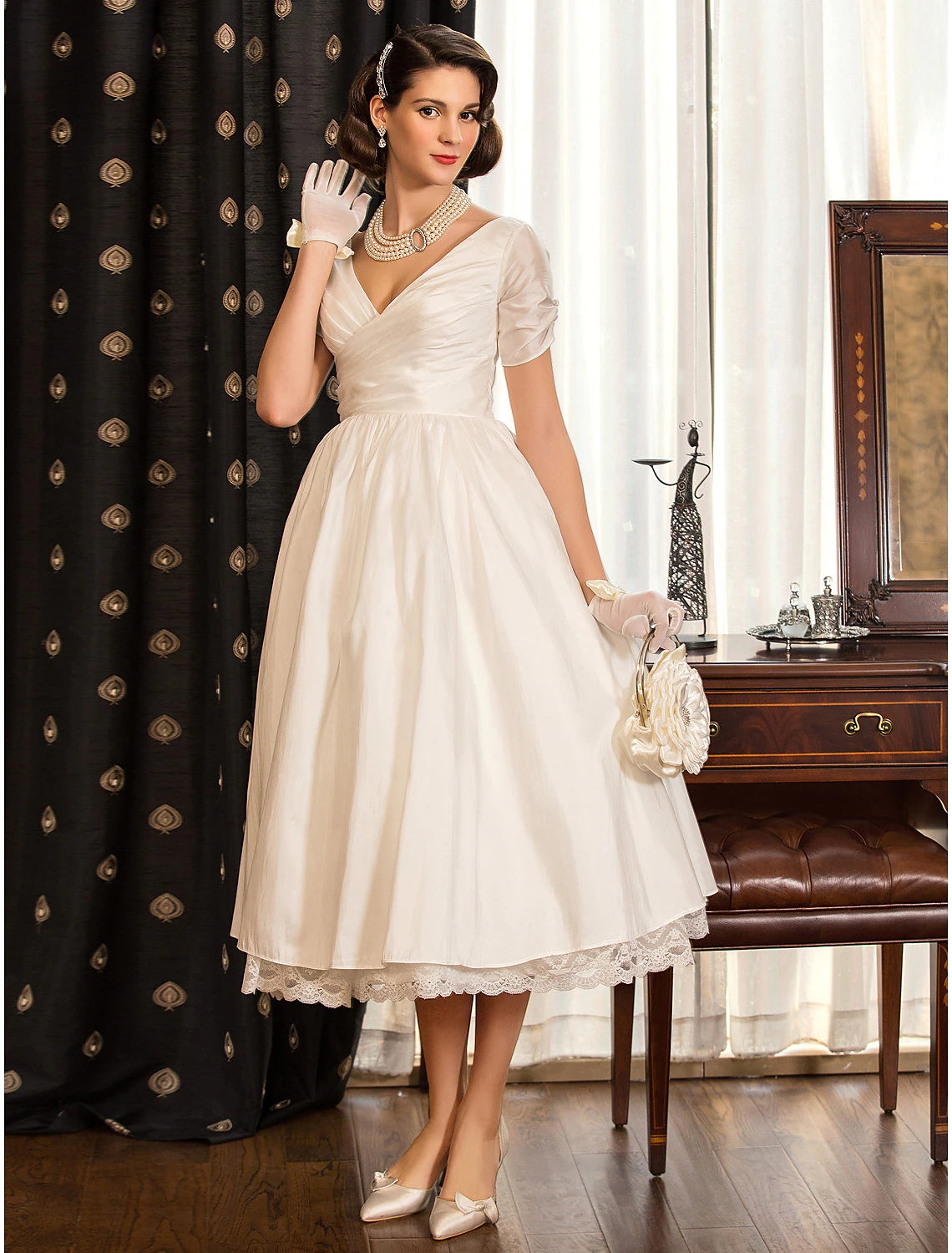 Front view of an elegant vintage A-line V-neck white tea length dress with lace details.