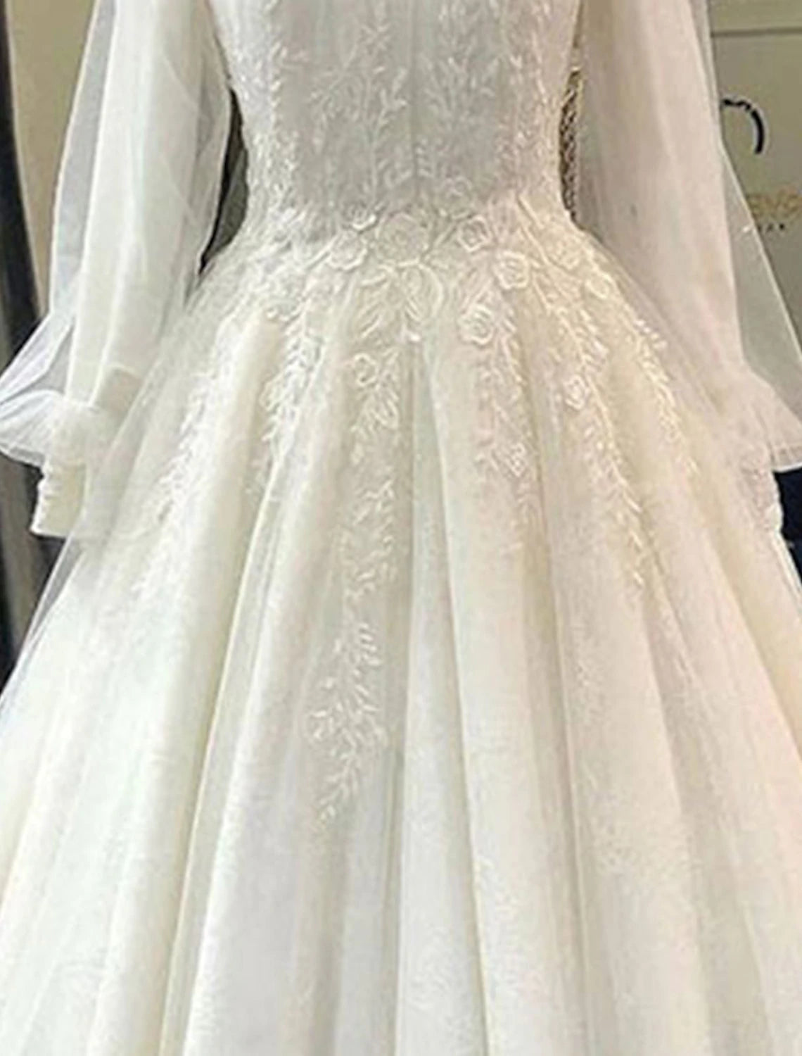 Close-up of the intricate lace detailing and high neckline on a bridal ball gown.