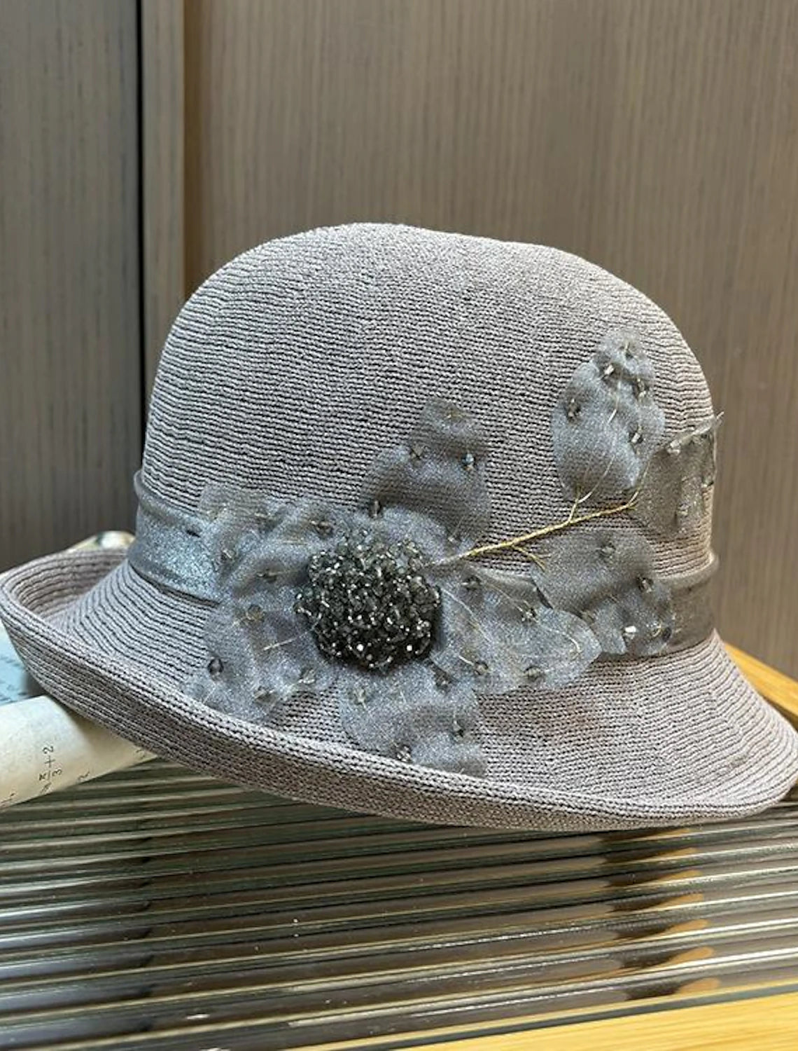 Side view of a black fascinator headpiece featuring delicate feather details.