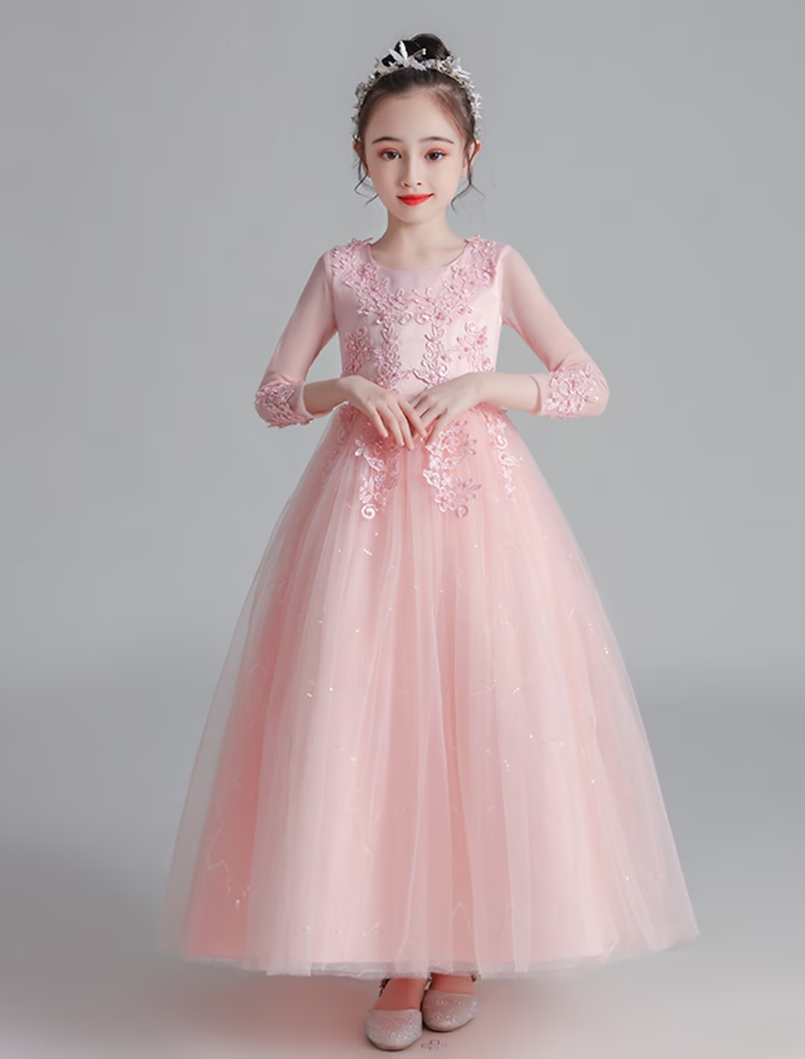 Little girl wearing an elegant white maxi dress with floral and bow embellishments, featuring 3/4 sleeves.