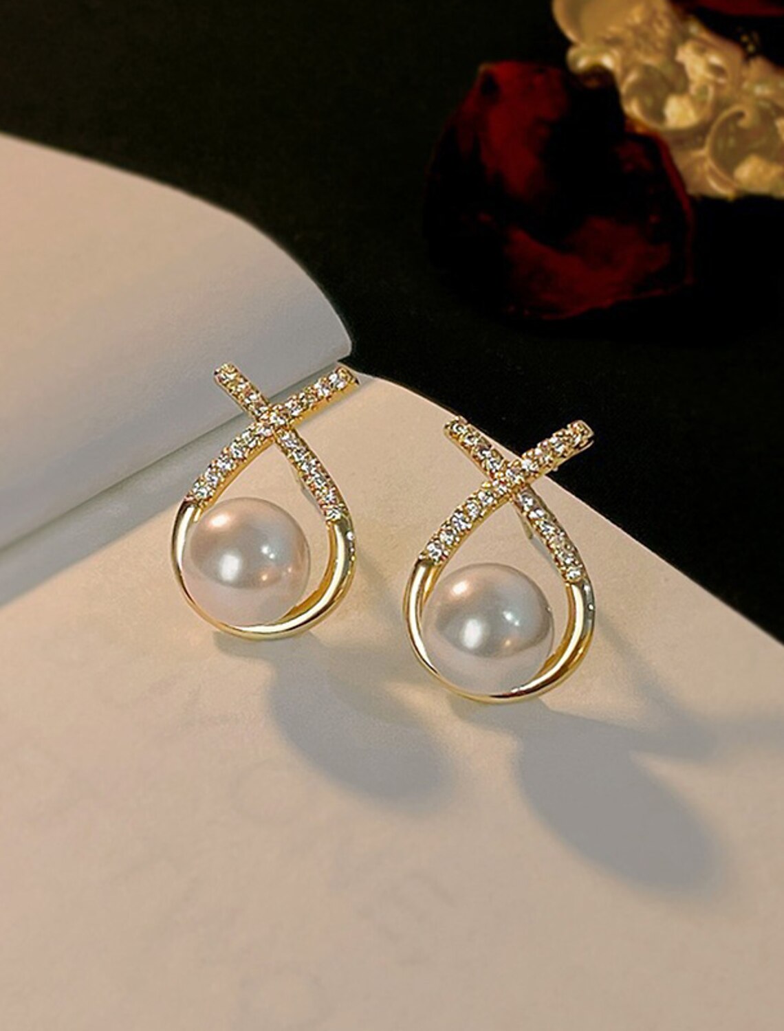 Pair of white imitation pearl stud earrings on a display.