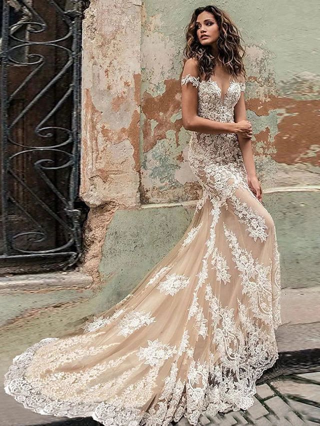 Close-up of the lace appliques and off-shoulder cap sleeve on a white wedding dress.