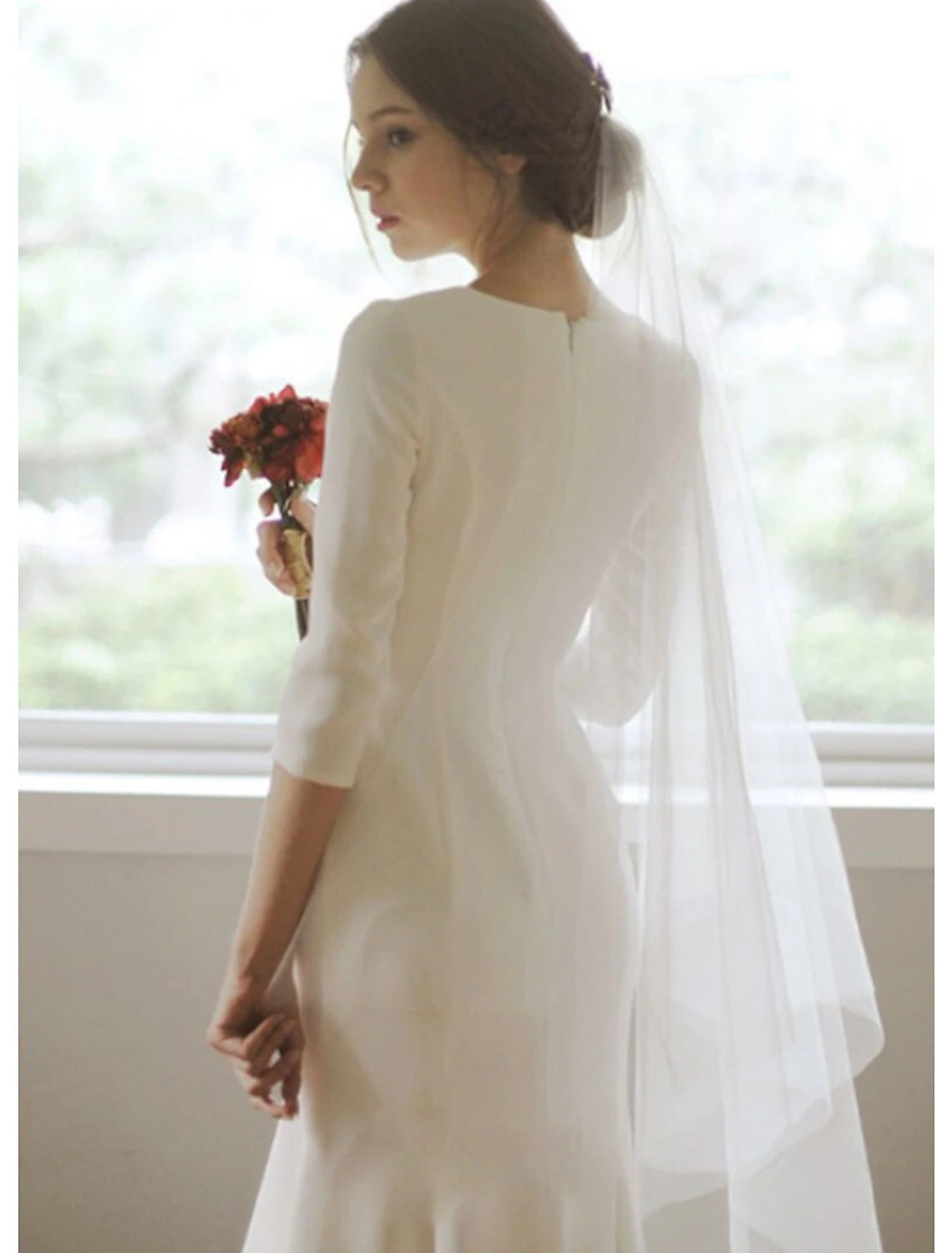 Side view of a white satin mermaid bridal gown featuring an asymmetrical design.