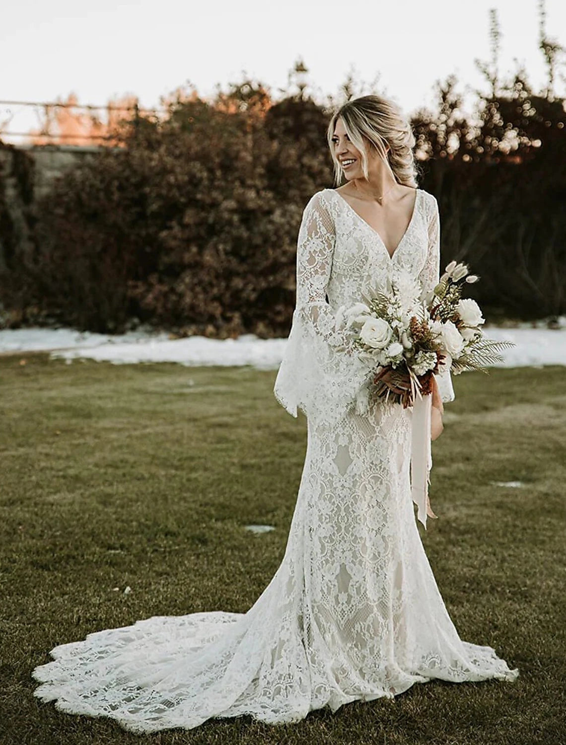 Full view of the white mermaid V-neck long sleeve lace wedding dress with a court train.