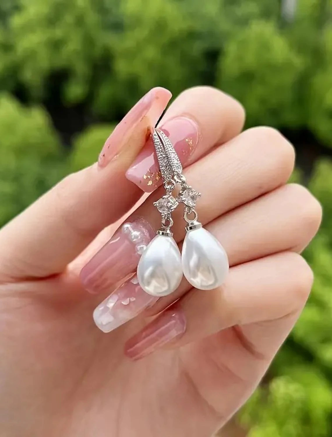 White pearl drop earrings worn by a model.