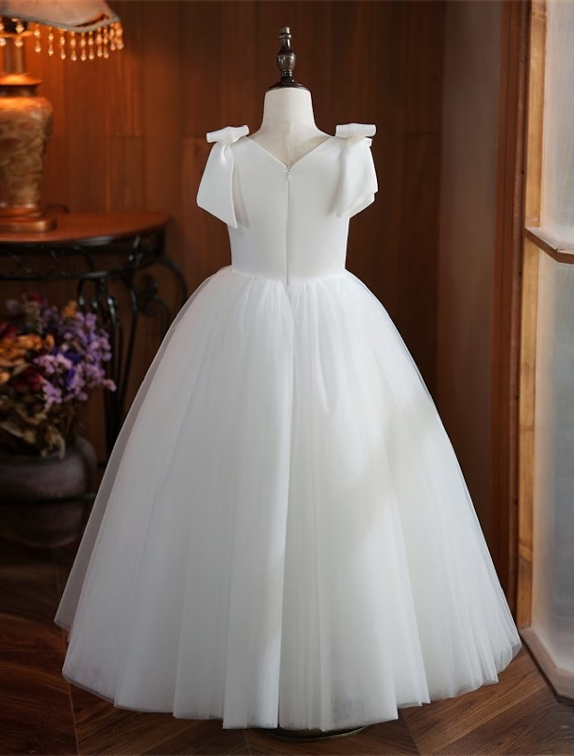 Girl wearing a white sleeveless princess dress, side view.