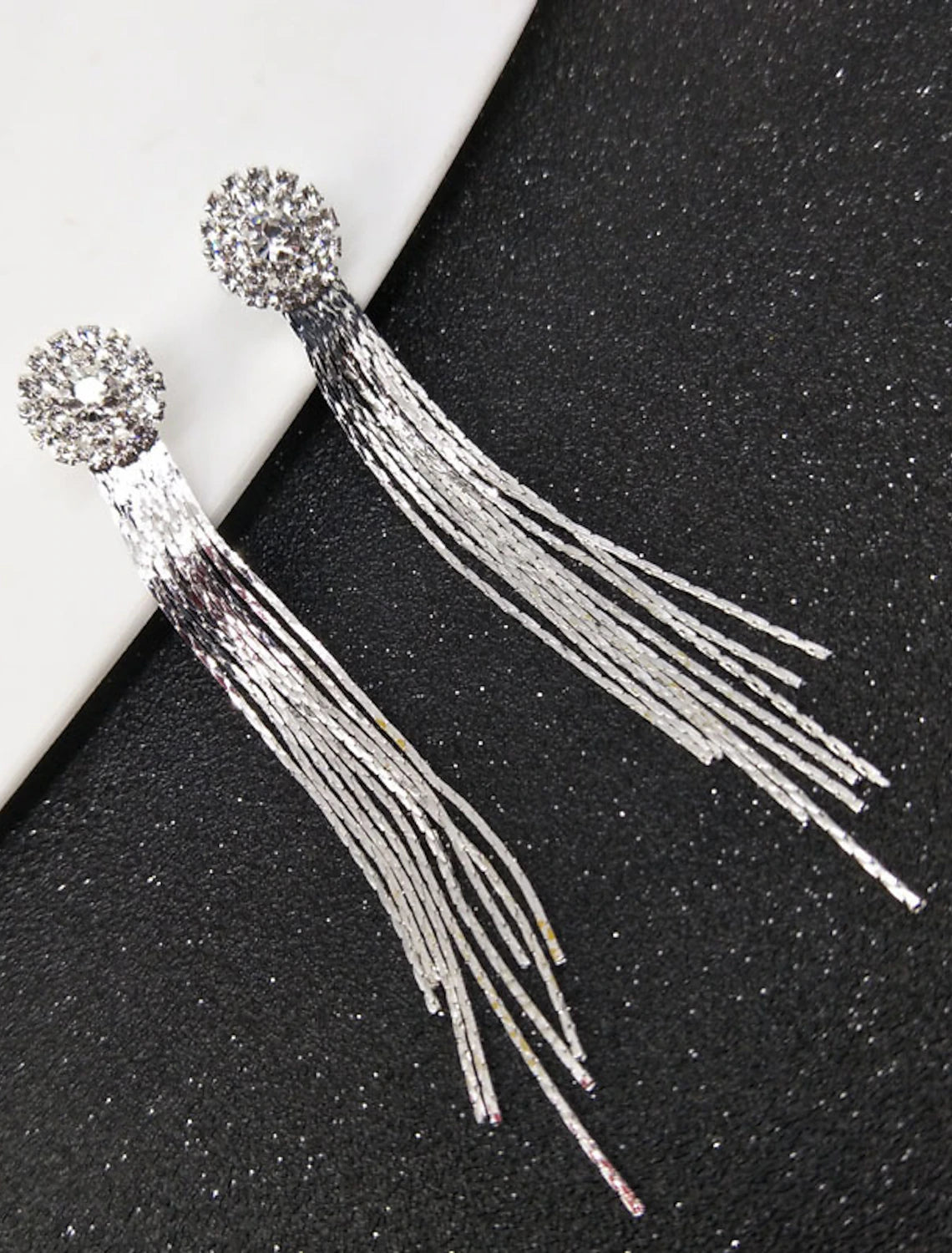 Detailed view of white tassel fringe drop earrings.