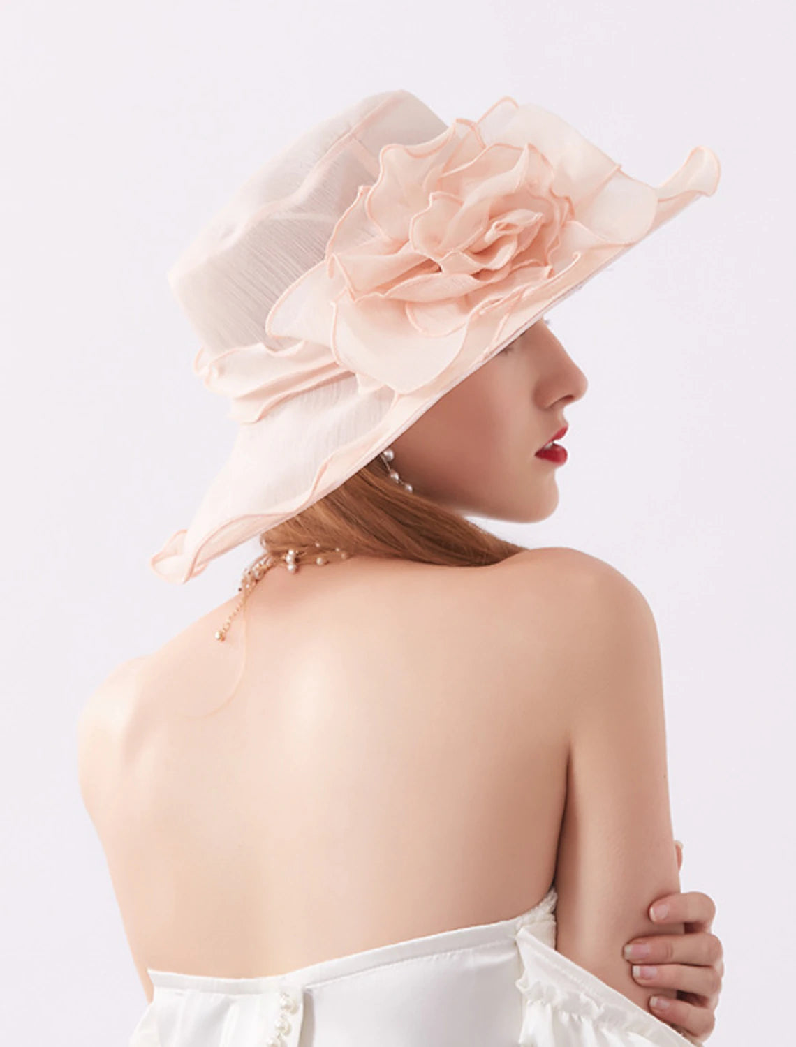 Side view of a woman wearing a wide brim organza hat with flower details.