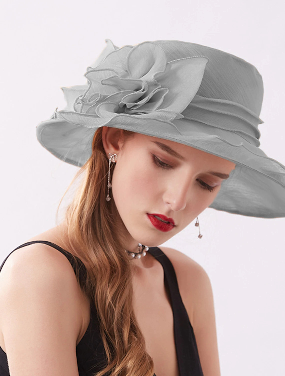 Woman posing in a stylish organza headpiece with a wide brim.