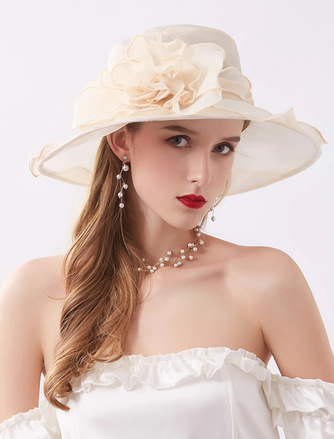 Woman in a white dress wearing a large organza sun hat with appliques.