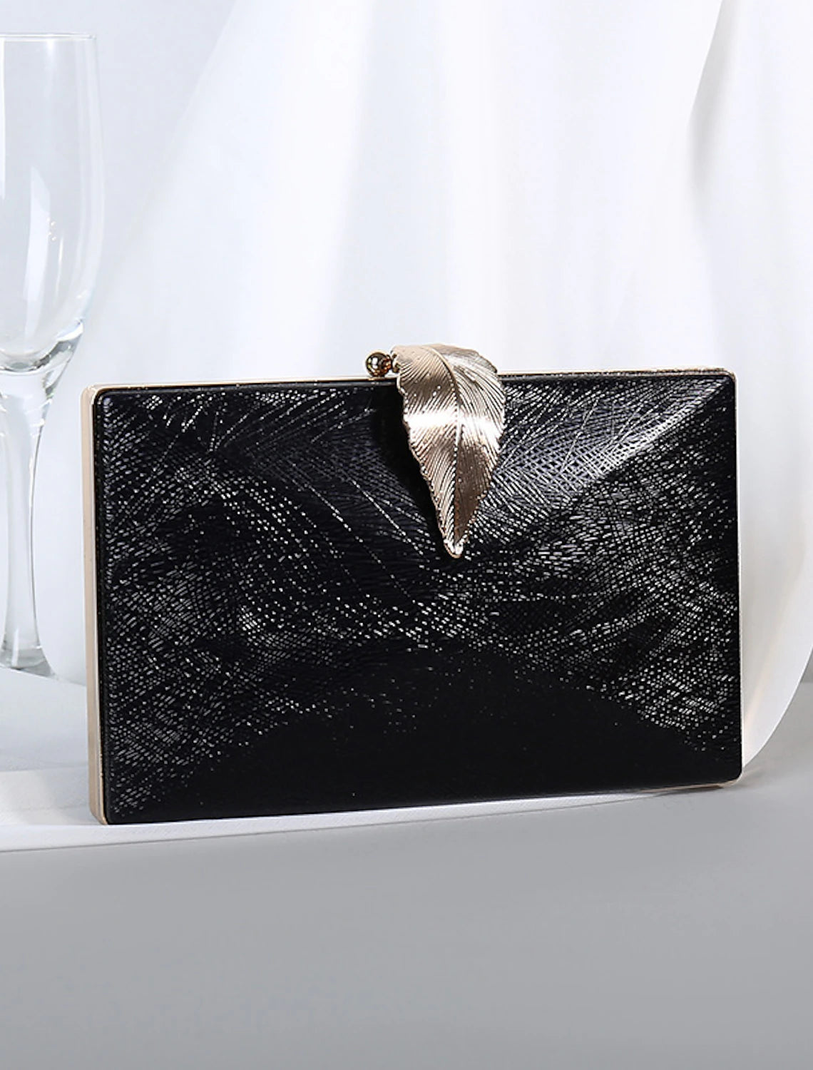 Close-up of the clutch bag's solid texture and refined hardware.
