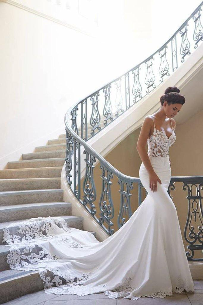 Mermaid wedding dress with spaghetti straps and backless design, featuring applique details.
