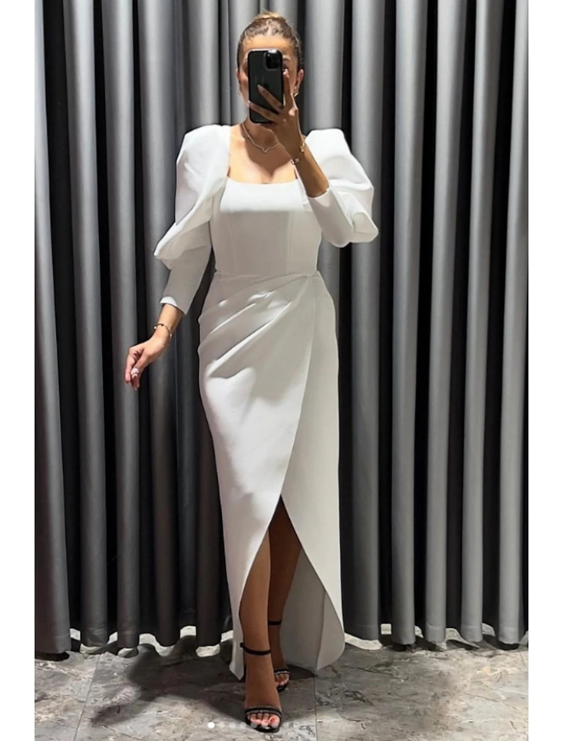 Model wearing a black sheath column evening dress with square neck and 3/4 sleeves.