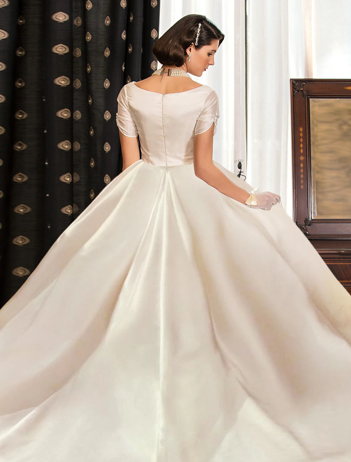 Close-up of the V-neck and short sleeve detail on a satin wedding dress.