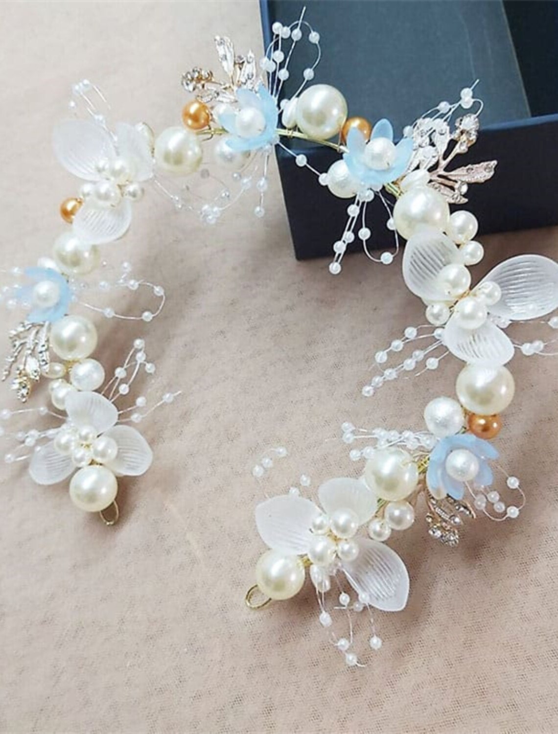 White floral garland headband displayed on a surface.