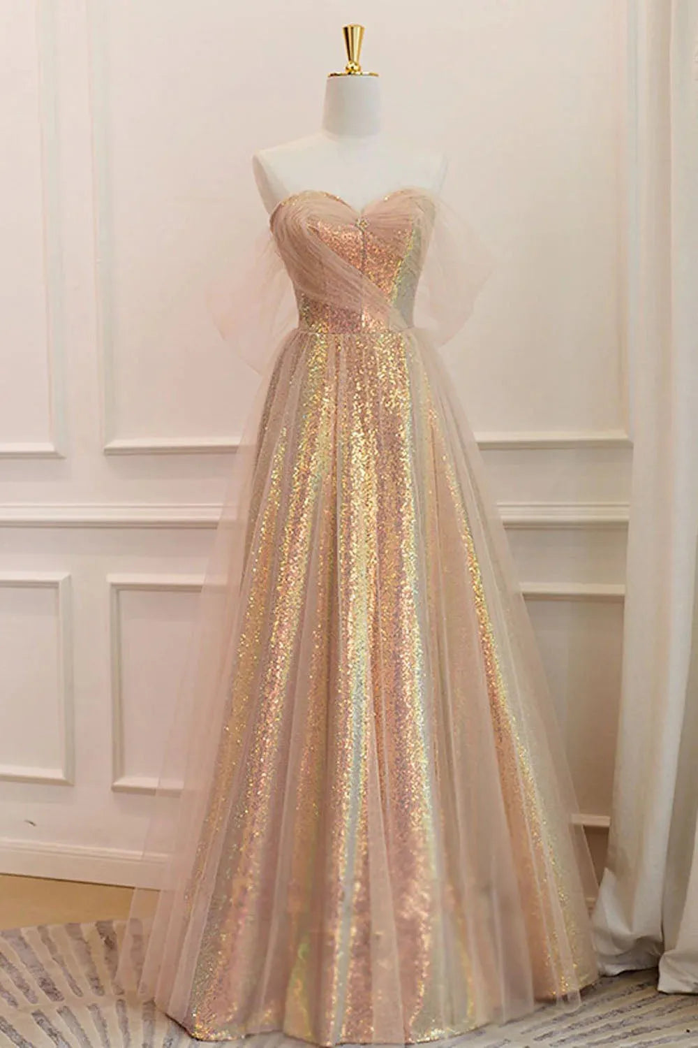 Woman wearing a dazzling A-line off-shoulder sequin long prom gown.