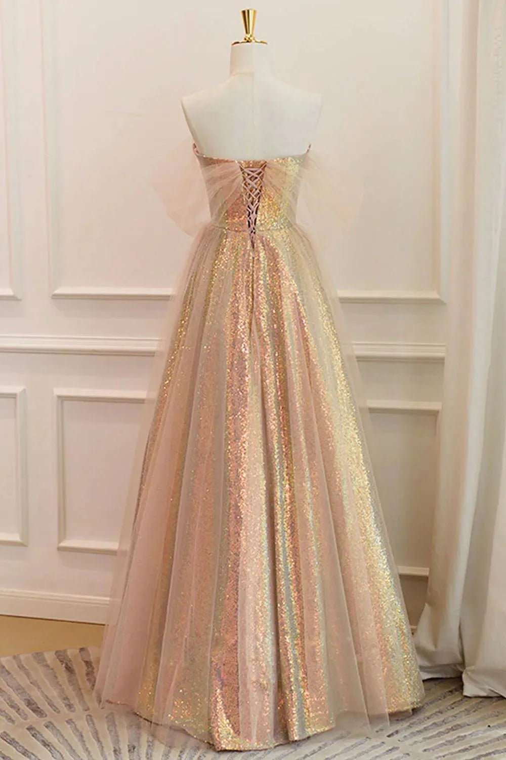 Back view of a woman in an elegant A-line sequin off-shoulder formal dress.
