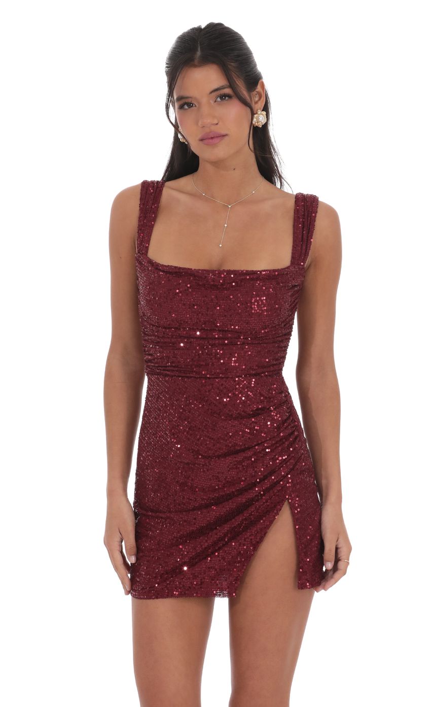 Model wearing a glamorous burgundy sequin mini homecoming dress with a square neckline and back bow.