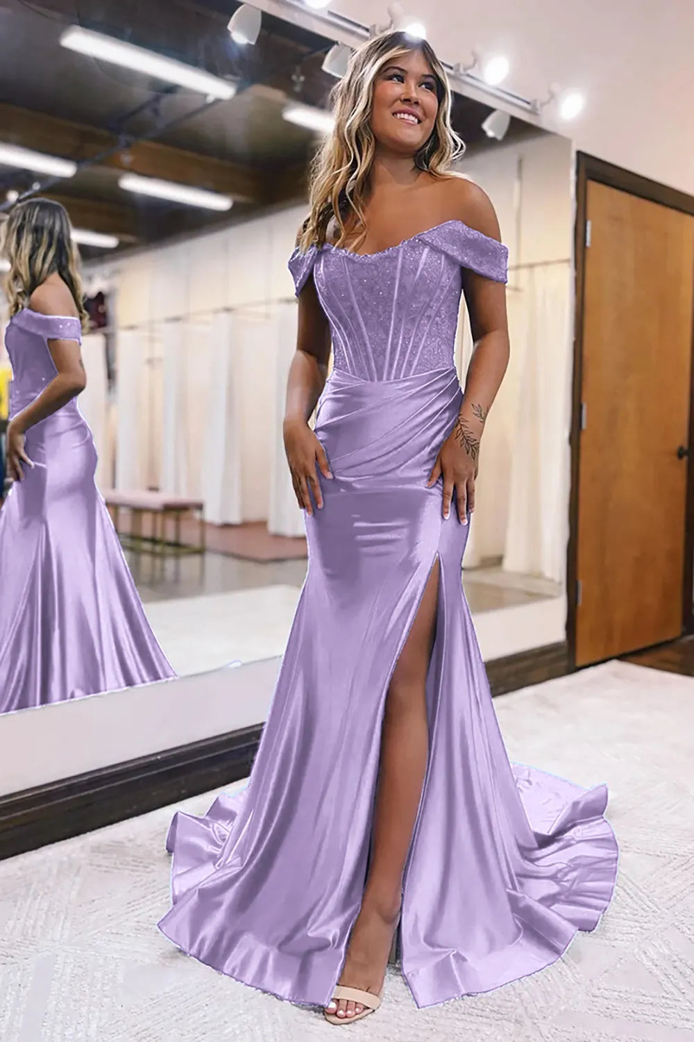 Model wearing a lilac off-shoulder mermaid gown with a high leg split.