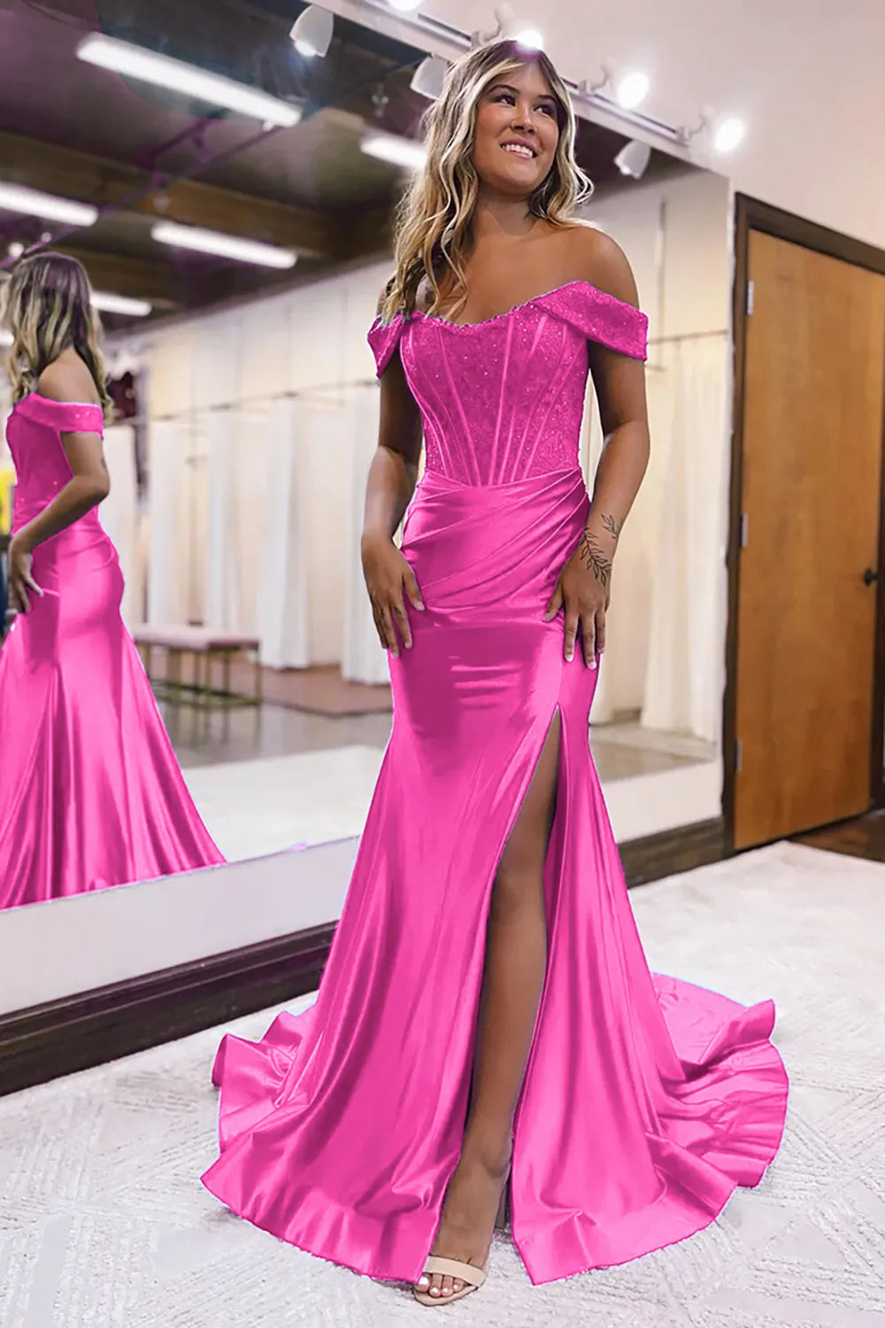 Model wearing a fuchsia off-shoulder mermaid dress with a dramatic split.